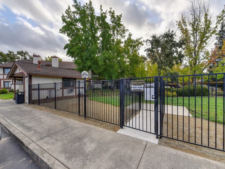 Dog Park Entrance with Sidewalk, Gate, Trees, Grass, Apartment Exterior